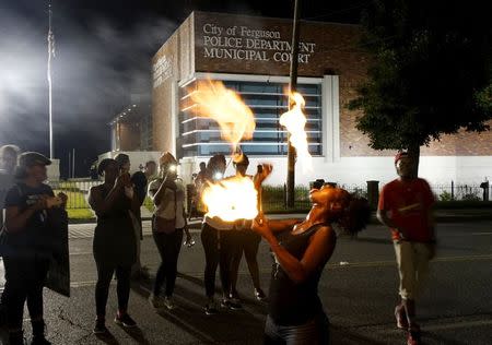 Laura Charles performs with fire sticks during a protest outside the police department in Ferguson, Missouri August 8, 2015. REUTERS/Rick Wilking