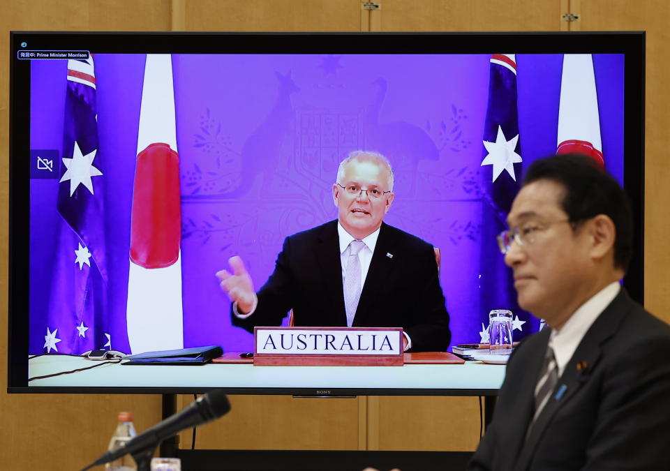 Japan's Prime Minister Fumio Kishida, right, and Australia's Prime Minister Scott Morrison, seen on screen, attend a virtual summit to sign the Reciprocal Access Agreement, at Kishida's official residence in Tokyo, Japan Thursday, Jan. 6, 2022. The leaders of Japan and Australia signed a “landmark” defense agreement Thursday that allows closer cooperation between their militaries and stands as a rebuke to China's growing assertiveness in the Indo-Pacific region. (Issei Kato/Pool Photo via AP)