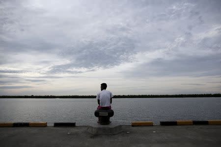 A Bangladeshi migrant who arrived recently by boat sits on a dock near a temporary shelter in Kuala Langsa, in Indonesia's Aceh Province May 25, 2015. REUTERS/Darren Whiteside