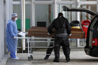 Health workers and undertakers place a coffin into a hearse at the entrance of the emergency area for COVID-19, at the University Hospital of Brasilia, in Brasilia, Brazil, Wednesday, Aug. 5, 2020. (AP Photo/Eraldo Peres)