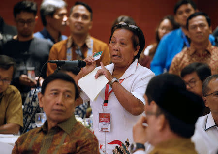 Bali bombing survivor Chusnul Khotimah (C) stand behind Indonesia Chief Security Minister Wiranto (L) as she speaks during a meeting between former militants and victims in Jakarta, Indonesia, February 28, 2018. REUTERS/Beawiharta