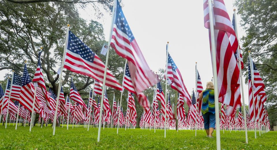 A volunteer walks through the Field of Valor installation at the former Mullet Festival grounds in Niceville. The flags honor service members from Florida who were killed in Iraq and Afghanistan.