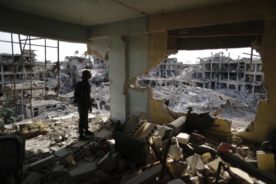 A Syrian soldier stands guard inside a destroyed apartment in the Palestinian refugee camp of Yarmouk in the Syrian capital Damascus, Syria, Saturday, Oct. 6, 2018. Bulldozers and trucks are working to clear tons of rubble from the main streets. The camp, once home to the largest concentration of Palestinians outside the territories housing nearly 160,000 people, has been gutted by years of war. (AP Photo/Hassan Ammar)