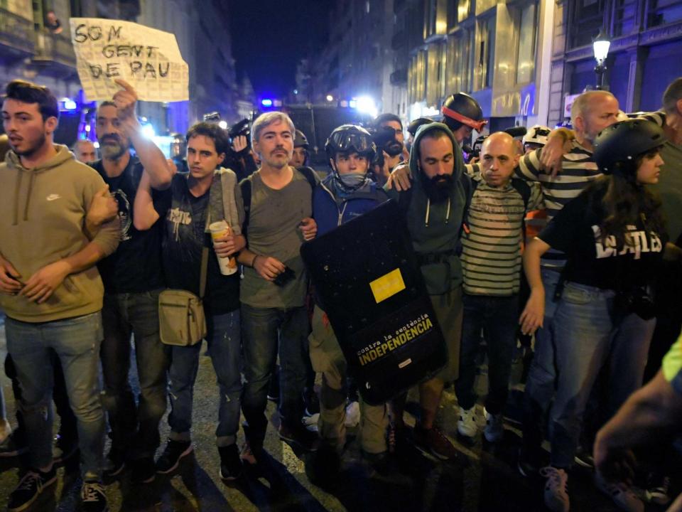 Protesters make a cordon between police and a sit-in, a day after nearly 200 people were hurt in another night of violent clashes in Catalonia: Llius Gene/AFP via Getty Images