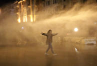 An anti-government protester is sprayed by a water canon during ongoing protests against the political elites who have ruled the country since decades, in Beirut, Lebanon, Sunday, Jan. 19, 2020. Lebanese security forces used tear gas, water cannons and rubber bullets in clashes with hundreds of anti-government protesters outside the country's Parliament on Sunday, as violence continued to escalate in a week of rioting in the capital. (AP Photo/Hassan Ammar)