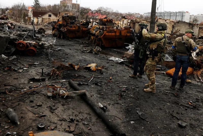 A serviceman uses his mobile phone to film a destroyed Russian tank and armoured vehicles, amid Russia's invasion on Ukraine in Bucha, in Kyiv region