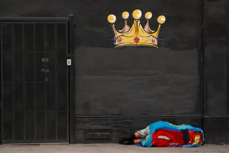 A homeless person sleeps on the sidewalk in the skid row area of downtown Los Angeles