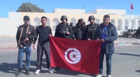 Tunisian authorities pose with a Tunisian flag at a site after an attack by Islamist fighters on an army and police barracks in the town of Ben Guerdan, Tunisia, near the Libyan border, in this March 7, 2016 still image taken from video. REUTERS/Reuters TV