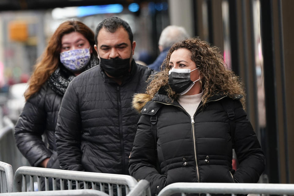 Pedestrians wear protective masks during the coronavirus pandemic in Times Square Thursday, Dec. 31, 2020, in New York. (AP Photo/Frank Franklin II)