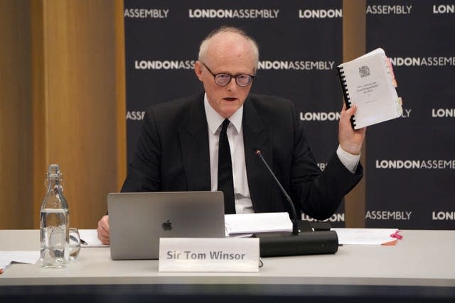 Sir Thomas Winsor holding up a copy of his report