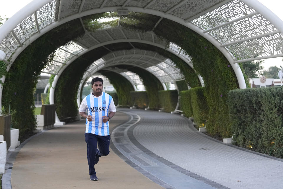 A fan in a Messi jersey runs at Al Gharafa Park in Doha, Qatar, Thursday, Nov. 24, 2022. Qatar unveiled a plan last October to cut its emissions by a quarter by 2030. Then, Russia invaded Ukraine and made the Persian Gulf nation's liquid natural gas only more sought after. Demand for fossil fuels has brought immense wealth to Qatar, but in the coming decades, it could also make one of the world's hottest places unlivable. (AP Photo/Abbie Parr)