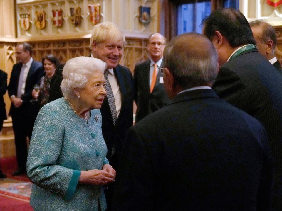 Britain's Queen Elizabeth II (L) and Britain's Prime Minister Boris Johnson (2L) greet guests during a reception to mark the Global Investment Summit, at Windsor Castle in Windsor, west of London on October 19, 2021.