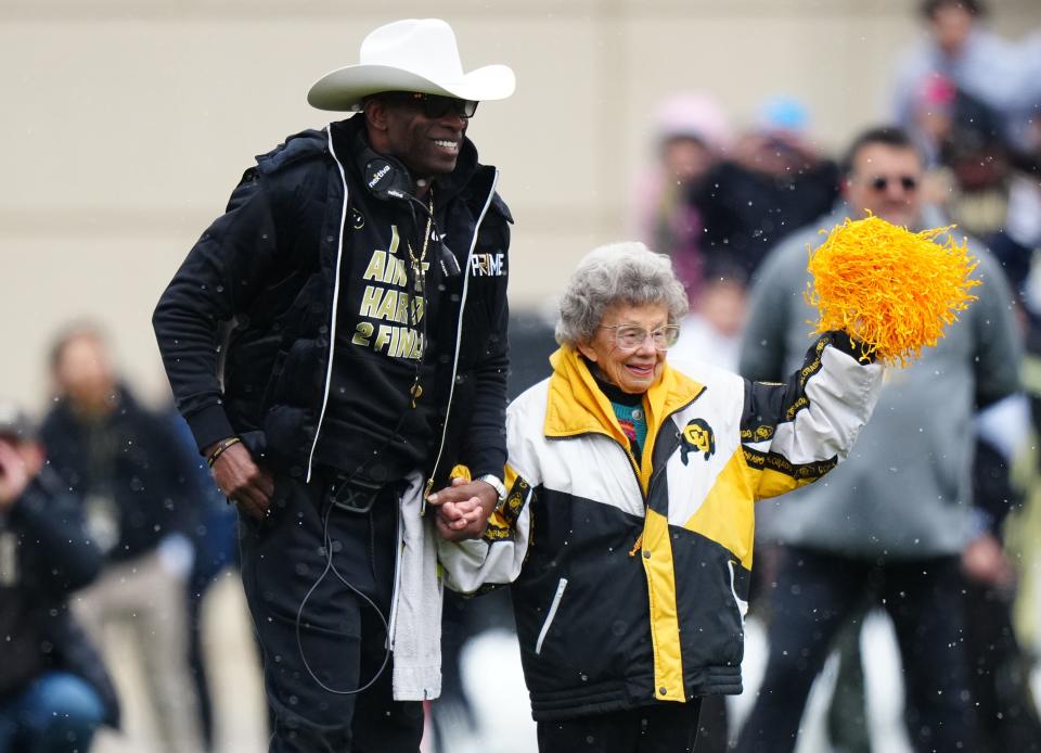 Colorado football coach Deion Sanders walks onto Folsom Field with Peggy Coppom before the start of the spring game in April.