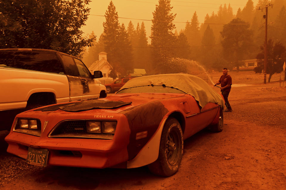 William Deal wets down his 1977 Trans Am as the Dixie Fire approaches Crescent Mills in Plumas County, Calif., Saturday, July 24, 2021. Deal, who lives in a community under evacuation orders, planned to stay to defend his home from the fire. (AP Photo/Noah Berger)