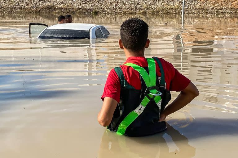 Esta fotografía publicada en la cuenta de la Media Luna Roja Libia en la plataforma X (anteriormente Twitter) el 14 de septiembre de 2023 muestra a un miembro de pie en una zona inundada cerca de un vehículo sumergido tras las inundaciones tras la tormenta mediterránea 