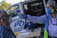 A Madrid Emergency Service (SUMMA) health worker checks the temperature of a man prior conducting a rapid antigen test for COVID-19 in the southern neighbourhood of Vallecas in Madrid, Spain, Tuesday, Sept. 29, 2020. Madrid has a rate of infection 2.5 times higher than the national average, which is already three times the European average, including the UK. (AP Photo/Bernat Armangue)