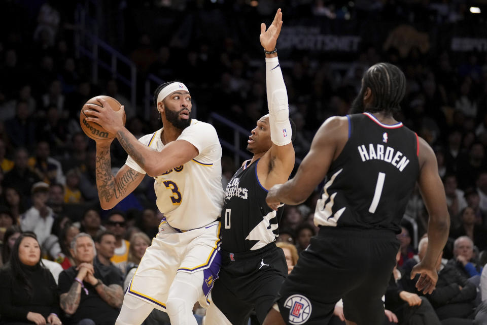 Los Angeles Lakers forward Anthony Davis (3) is defended by Los Angeles Clippers guard Russell Westbrook (0) as Clippers guard James Harden (1) watches during the first half of an NBA basketball game in Los Angeles, Sunday, Jan. 7, 2024. (AP Photo/Eric Thayer)