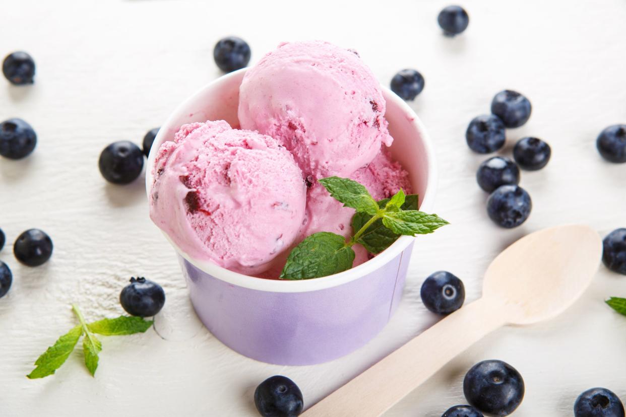 Blueberry ice cream or frozen yogurt and sprig of mint, with fresh berries and wooden spoon.