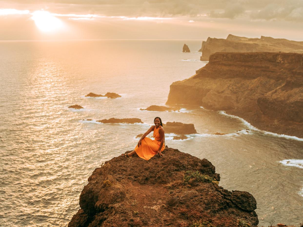 Monet Hambrick sitting on a seaside cliff ledge in Portugal.