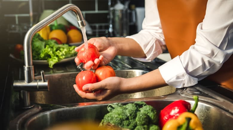 person washing tomatoes in sink