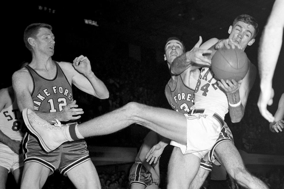 FILE - North Carolina State's Ronnie Shavlik takes the ball from Wake Forest's Jack Williams, obscured behind Shavlik, during the Atlantic Coast Conference NCAA college basketball tournament in Raleigh, N.C., March 3, 1956. (AP Photo/Rudolph Faircloth, File)