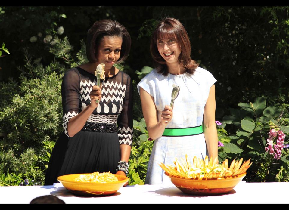 U.S. first lady Michelle Obama, left, and Samantha Cameron, the wife of Britain's Prime Minister David Cameron,  hold up serving tongs towards the media as they serve food during a barbecue in the garden of 10 Downing Street in London, Wednesday, May 25, 2011.  The barbecue Wednesday, where Cameron, U.S. President Barack Obama and their wives served food, was attended by members of the military from the UK and the U.S.  (AP Photo/Matt Dunham-Pool)