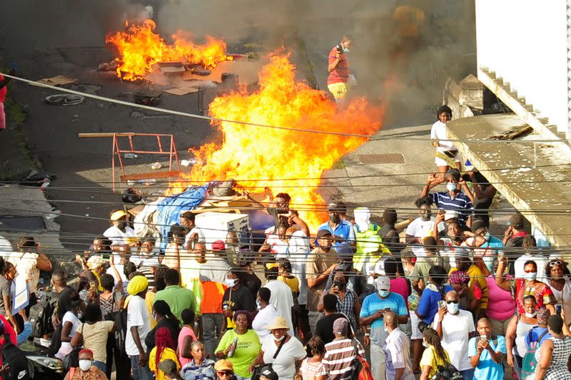 A fire burns near people protesting against amendments to the Public Health Act in Kingstown