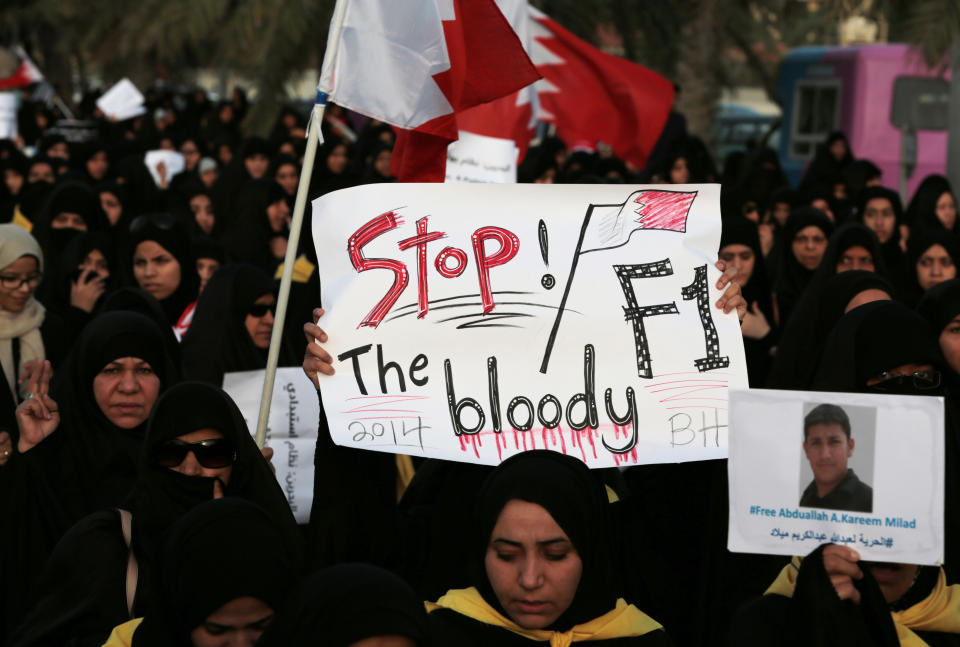 A Bahraini protester raises a sign against the Formula One Bahrain Grand Prix during a protest in Saar, Bahrain, Friday, April 4, 2014. Tens of thousands of Bahraini anti-government protesters carrying signs and images of political prisoners waved national flags and signs against the Formula One Bahrain Grand Prix, which is being held Sunday in the Gulf island kingdom. (AP Photo/Hasan Jamali)