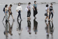 People wearing face masks to protect against the spread of the new coronavirus walk on a beach on a national holiday in Fujisawa, Kanagawa prefecture, near Tokyo, Thursday, July 23, 2020. (AP Photo/Koji Sasahara)