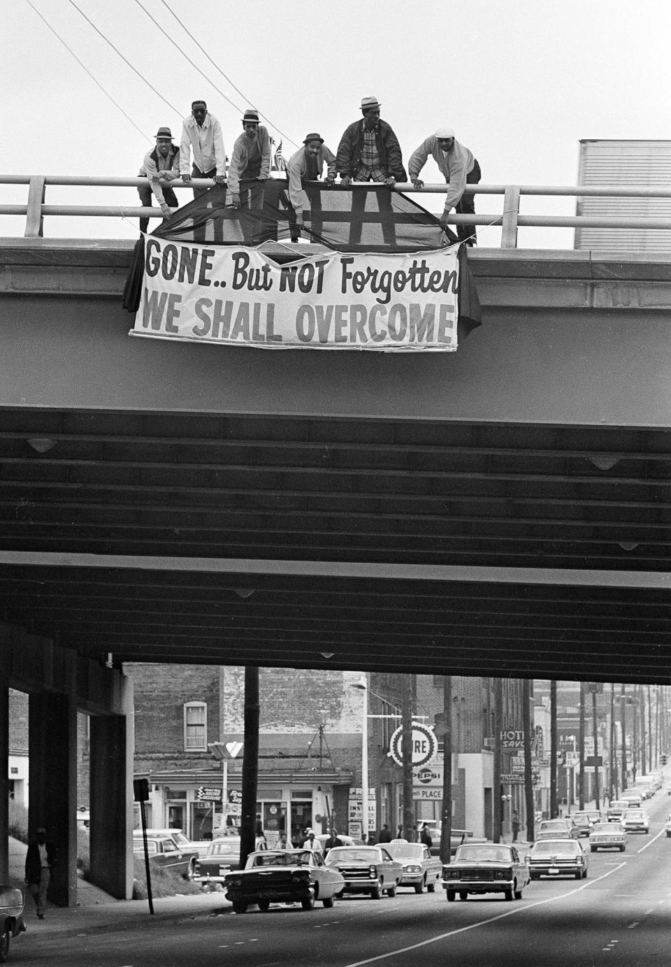 <p>Six men hang a sign in honor of King on an expressway bridge near the Southern Christian Leadership Conference headquarters in Atlanta. (Photo: Toby Massey/AP) </p>