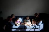 Anastasia Domini, right, helps her daughter Una read alongside siblings Aksinia, center right, Mikhail, left, and Agata, at their home in Buenos Aires, Argentina, Saturday, April 22, 2023. In the northwestern Russian city of Petrozavodsk, Anastasia, 34, and her wife Anna, 44, barely told anyone about their partnership and four children—two sets of twins. There was a constant fear authorities would take their children away “and put them in an orphanage,” Anastasia Domini said. (AP Photo/Natacha Pisarenko)