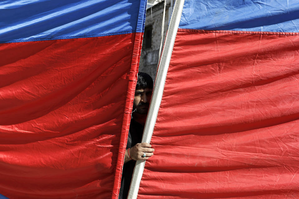 A man looks through a banner as Shiite men flagellates