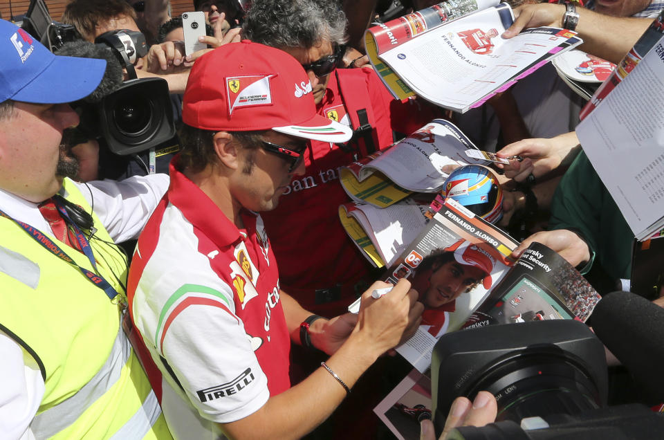 Ferrari driver Fernando Alonso of Spain signs autographs for fans as he arrives at Albert Park ahead of the Australian Formula One Grand Prix in Melbourne, Australia, Thursday, March 13, 2014. (AP Photo/Rob Griffith)