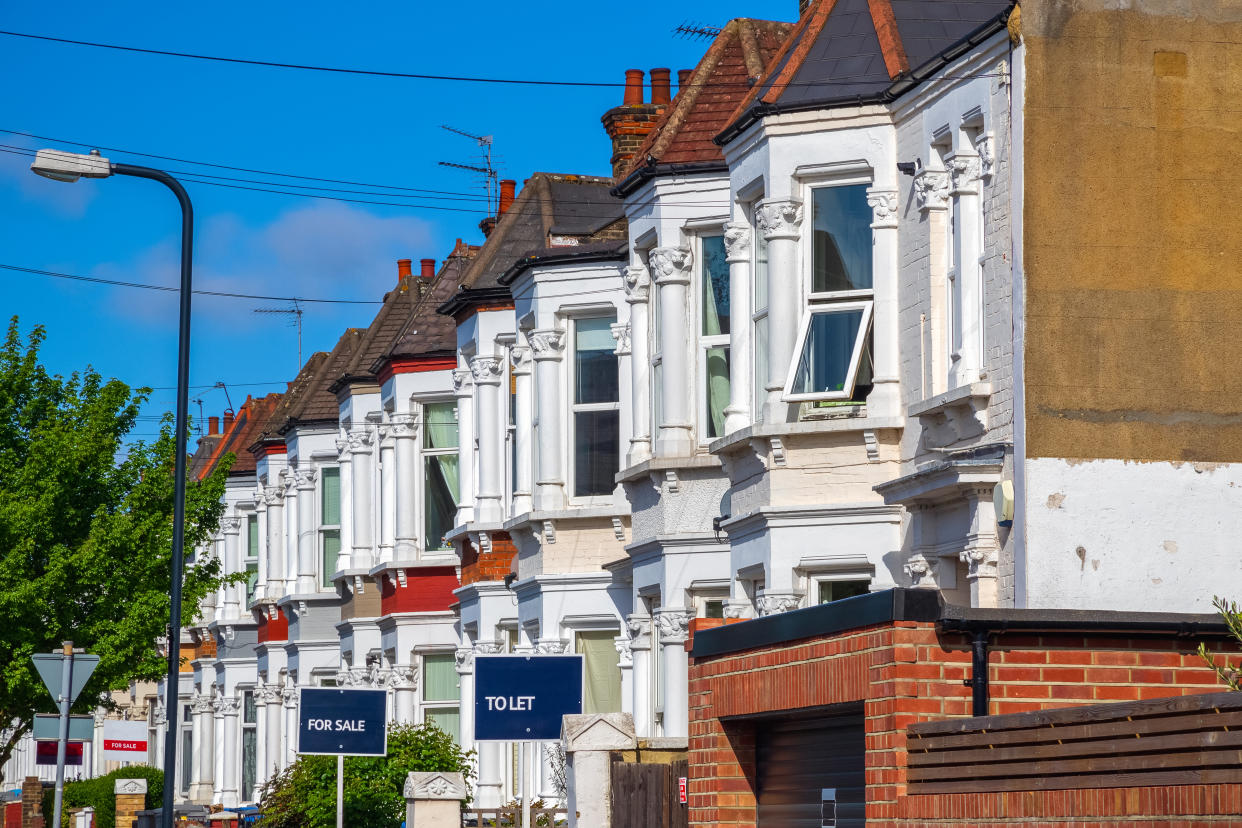 A row of typical British terraced houses around Kensal Rise in London with estate agent boards