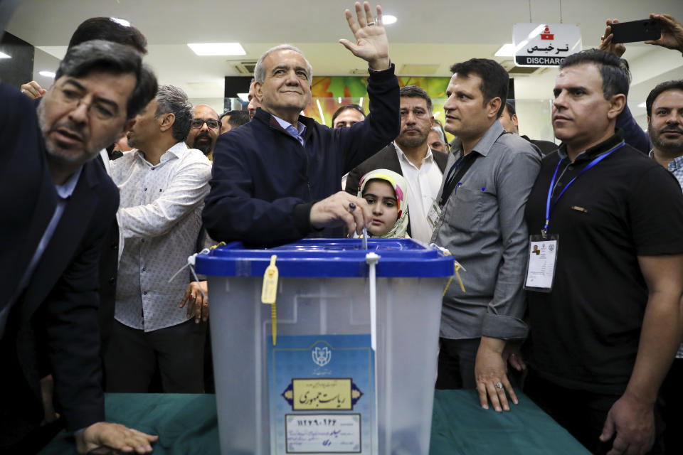 En esta imagen, distribuida por la agencia noticiosa iraní ISNA, el candidato presidencial reformista Masoud Pezeshkian deposita su voto mientras saluda a la prensa en una casilla electoral, el 28 de junio de 2024, en Teherán, Irán. (Majid Khahi, ISNA vía AP)