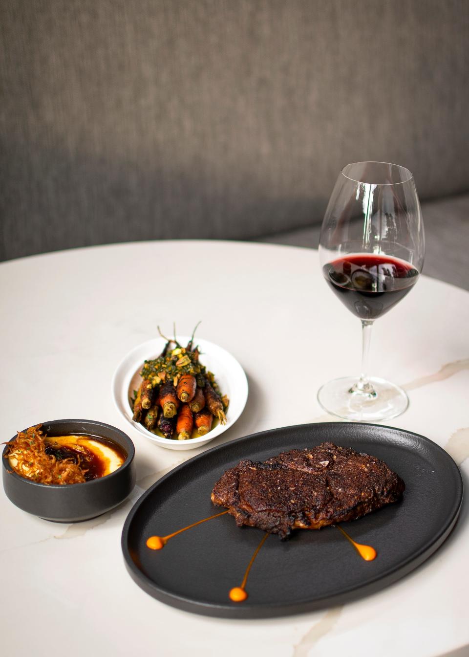 The ribeye steak, served with sides of heirloom carrots topped with a pistachio pesto and potato puree with chicken jus, at The Americano in Scottsdale on Dec. 9, 2021.
