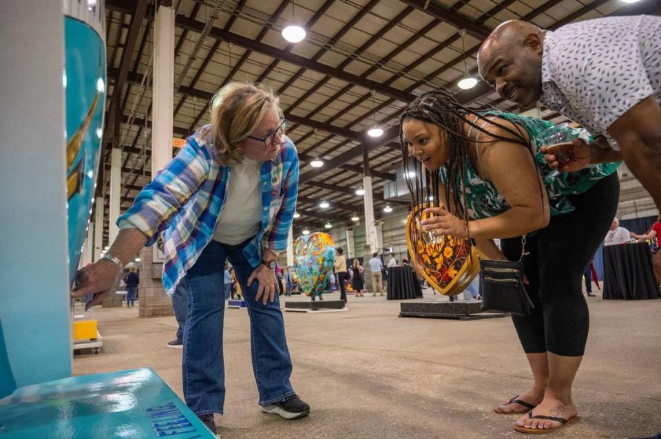 Artist Ruthie Messer Wolkey explains some Easter eggs on her heart display titled “Jazz & Blues in KC” to visitors Kelly LaGrant, left, and Brad Dacus Friday during the Parade of Hearts reveal kickoff event. Emily Curiel/ecuriel@kcstar.com