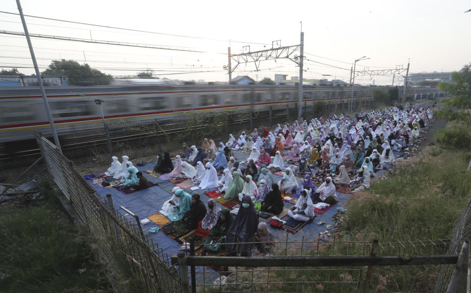 Muslim gather during Eid al-Fitr prayer marking the end of the holy fasting month of Ramadan on a street in Bekasi, West Java, Indonesia, Thursday, May 13, 2021. (AP Photo/Achmad Ibrahim)