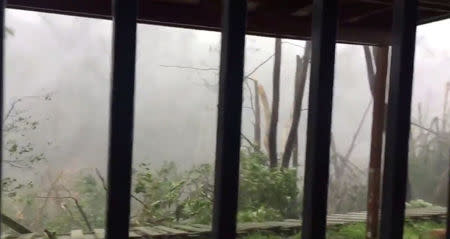 Strong winds bring down a fence of a house and causes destruction as Hurricane Maria hits Suan Juan, Puerto Rico September 20, 2017, in this still image from social media video. TWITTER/@ EAMOLERO/via REUTERS