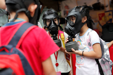 Children try on gas masks during a public fair which displays military equipments, in Taipei, Taiwan September 29, 2018. Picture taken September 29, 2018. REUTERS/Tyrone Siu