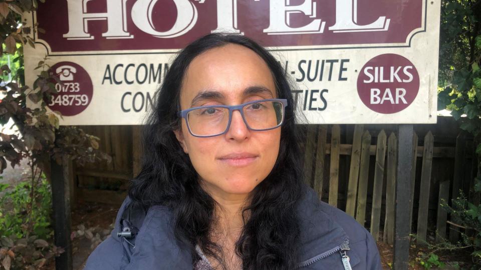 Sobia Khalid standing in front of a hotel sign and wooden fence