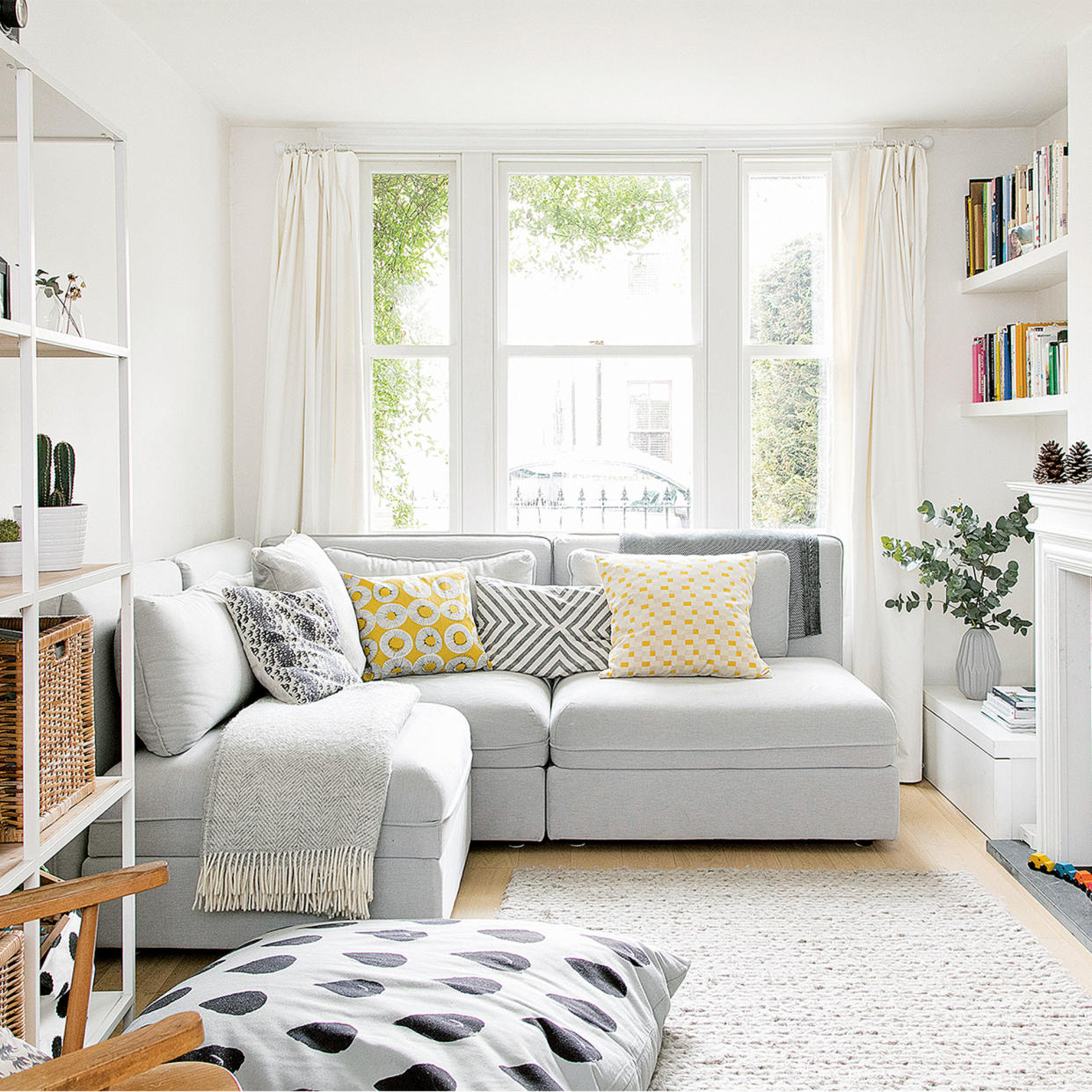  Small white living room with corner sofa and shelving unit plus rug. 