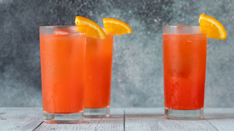 Three cocktails garnished with orange