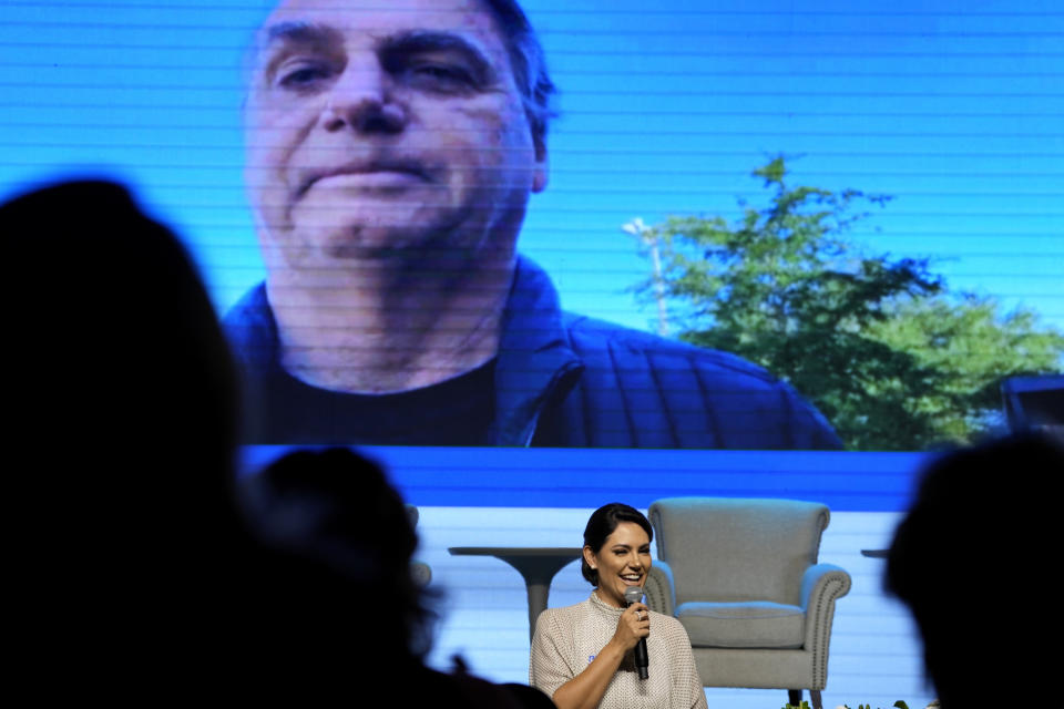 Former first lady Michelle Bolsonaro speaks at an event where she was presented as the new leader of PL Women by the Liberal Party (PL), in Brasilia, Brazil, Tuesday, March 21, 2023. Above is live video of her husband, former President Jair Bolsonaro, who attended the event virtually from Florida. (AP Photo/Eraldo Peres)