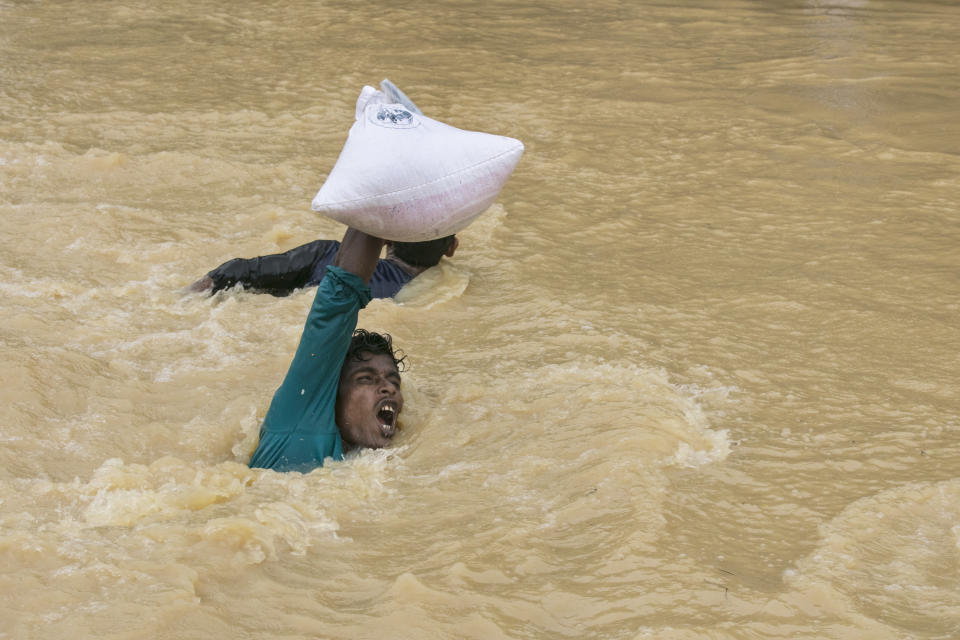 A man struggles to carry supplies across a stream as the monsoon rains continue to make life miserable for the displaced Rohingya on Sept. 17 in Kutupalong, Cox's Bazar, Bangladesh.