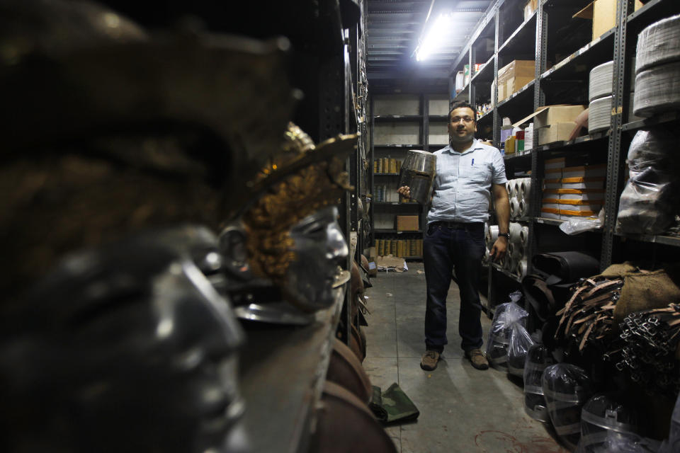 In this, June 2, 2012 photograph, Delhi businessman Ashok Rai, weapons and attire maker of war movies set from the 10th century to World War II, poses with a medieval helmet at his workshop in Sahibabad, India. From Hollywood war movies to Japanese Samurai films to battle re-enactments across Europe, Rai is one of the world's go-to men for historic weapons and battle attire. (AP Photo/Saurabh Das)