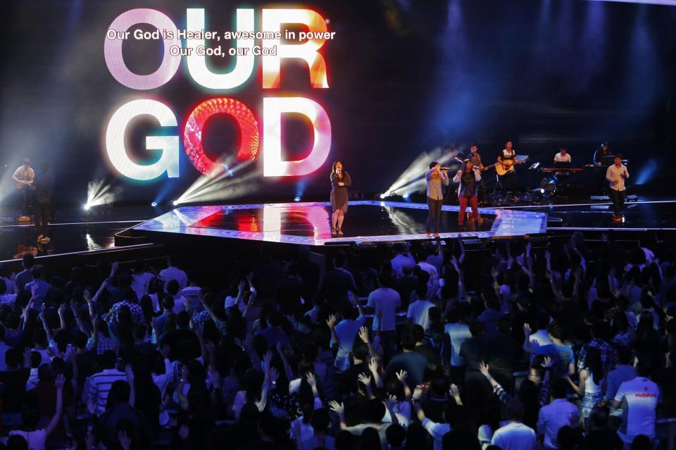 Worshippers attend a church service at the City Harvest Church in Singapore March 1, 2014. With a "prosperity gospel" that blends the spiritual and the material, City Harvest and other Pentecostal megachurches in the wealthy Asian city-state have perfected a popular and lucrative model. Now they are working to export it to the world and turn Singapore into a hub for evangelical Christianity. Picture taken March 1, 2014. To match Feature SINGAPORE-MEGACHURCHES/ REUTERS/Edgar Su (SINGAPORE - Tags: RELIGION)