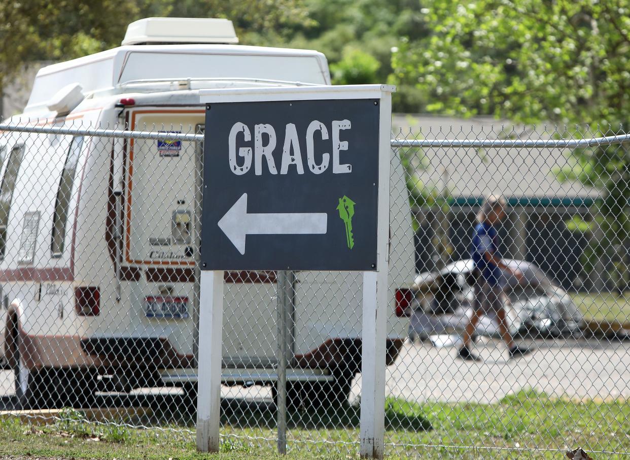 Residents of Grace Marketplace walk behind the closed fence at the homeless facility, in Gainesville, Fla. March 21, 2020. Residents and staff of Grace are voluntarily quarantining to prevent and contraction of spread of COVID-19 to the homeless community there.   [Brad McClenny/The Gainesville Sun]