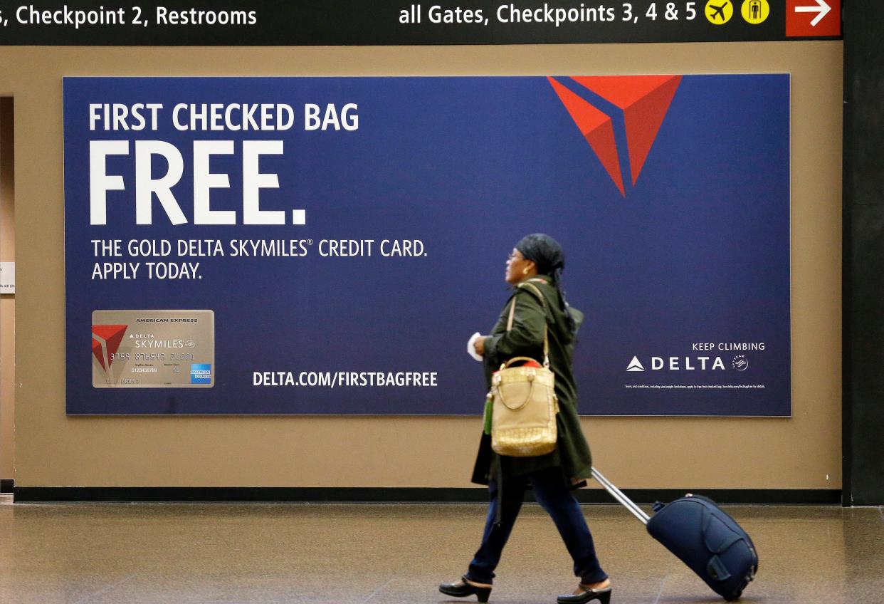 This file photo from March 24, 2015, shows a traveler passing a sign advertising a Delta Air Lines credit card at Seattle-Tacoma International Airport.