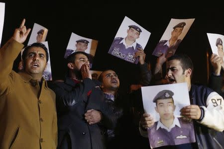 Relatives of Islamic State captive Jordanian pilot Muath al-Kasaesbeh hold up his pictures as they chant slogans demanding that the Jordanian government negotiate with Islamic state and for the release of Kasaesbeh, in front of the prime minister's building in Amman, January 27, 2015. REUTERS/Muhammad Hamed